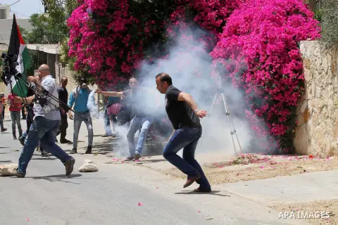 Palestinian protesters run for cover from tear gas fired by Israeli security forces during clashes following a demonstration against the expropriation of Palestinian land by Israel, on May 27, 2016 in the village of Kfar...
