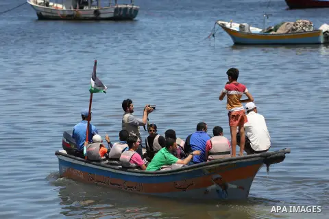 Palestinians hold flags as they ride a boat during a protest to break the siege, at the seaport of Gaza City May 30, 2016. Photo by Mohammed Asad