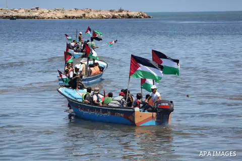 Palestinians hold flags as they ride a boat during a protest to break the siege, at the seaport of Gaza City May 30, 2016. Photo by Mohammed Asad