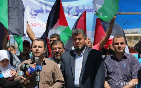 Palestinians hold flags during a protest to break the siege, at the seaport of Gaza City May 30, 2016. Photo by Mohammed Asad