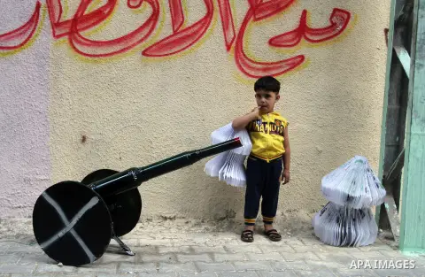 A Palestinian boy holds lantern as he stands next to a cannon of Ramadan that are used during the holy month of Ramadan in the Rafah refugee camp in southern Gaza Strip on May 30, 2016. Photo by Abed Rahim Khatib