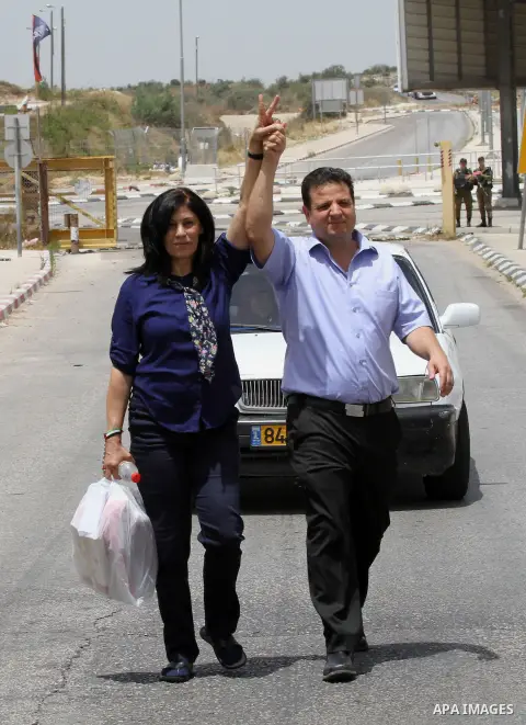 Prominent Palestinian lawmaker Khalida Jarrar walks flashing the sign for victory and holding the hand of the head of Israel's Arab parliamentary bloc Ayman Odeh as she walks through Jubara checkpoint near the northern W...