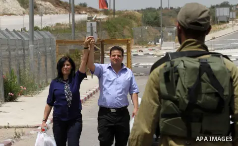 Prominent Palestinian lawmaker Khalida Jarrar walks flashing the sign for victory and holding the hand of the head of Israel's Arab parliamentary bloc Ayman Odeh as she walks through Jubara checkpoint near the northern W...