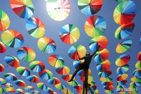 A Palestinian worker of a beachside café shop decorates its terrace with hanging colourful umbrellas as part of decorations for the Muslim holy fasting month of Ramadan in Gaza City, on June 9, 2016. Ramadan is sacred to...
