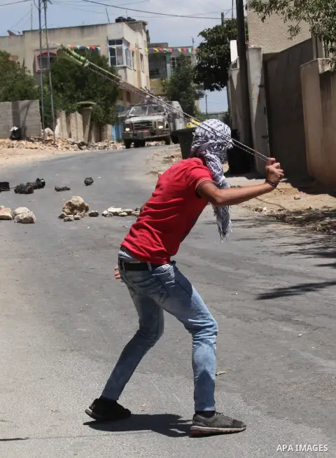 A Palestinian protester uses a slingshot to throw stones towards Israeli security forces during clashes following a demonstration against the expropriation of Palestinian land by Israel, on June 10, 2016. in the village...