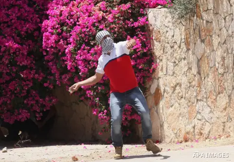 A Palestinian protester uses a slingshot to throw stones towards Israeli security forces during clashes following a demonstration against the expropriation of Palestinian land by Israel, on June 10, 2016. in the village...