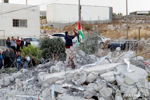 A Palestinian youth holds a Palestinian flag as he stands at the rubble of Palestinian teenager Murad Idais house who was accused of stabbing to death a 38-year old Israeli nurse in an attack in the Israeli Otniel settle...