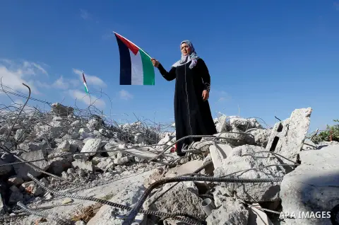 The mother of 15-year old Palestinian teenager Murad Idais who was accused of stabbing to death a 38-year old Israeli nurse in an attack in the Israeli Otniel settlement in January 2016 holds a Palestinian flag as she st...