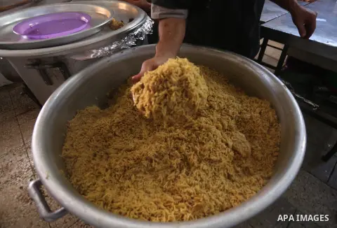 Palestinians prepare rice and meats as they wait for customers several hours before Iftar, the breaking of the day long Ramadan fast in Gaza City, on June 12, 2016. Muslims around the world refrain from eating, drinking...