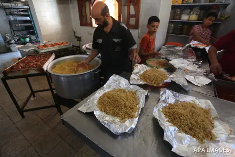 Palestinians prepare rice and meats as they wait for customers several hours before Iftar, the breaking of the day long Ramadan fast in Gaza City, on June 12, 2016. Muslims around the world refrain from eating, drinking...
