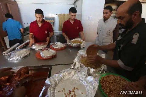 Palestinians prepare rice and meats as they wait for customers several hours before Iftar, the breaking of the day long Ramadan fast in Gaza City, on June 12, 2016. Muslims around the world refrain from eating, drinking...