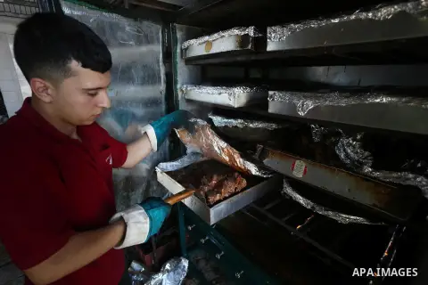 Palestinians prepare rice and meats as they wait for customers several hours before Iftar, the breaking of the day long Ramadan fast in Gaza City, on June 12, 2016. Muslims around the world refrain from eating, drinking...