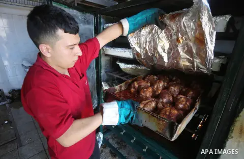 Palestinians prepare rice and meats as they wait for customers several hours before Iftar, the breaking of the day long Ramadan fast in Gaza City, on June 12, 2016. Muslims around the world refrain from eating, drinking...