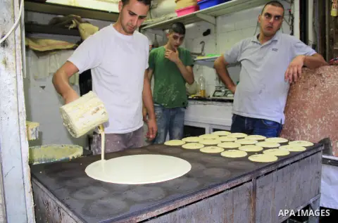 A Palestinian man prepares traditional pancakes known as ''Qatayef" at a market during the Muslim holy fasting month of Ramadan in Jerusalem's old city on June, 12, 2016. Ramadan is sacred to Muslims because it is during...