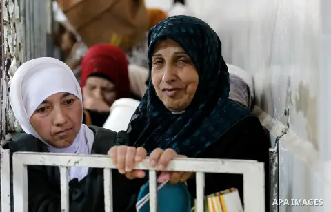 Palestinian families carry containers as they wait to receive free food for 'Iftar', the meal that breaks the daily fast during Ramadan in the West Bank city of Hebron, 13 June 2016. the "Ibrahimi Takiya" was founded in...