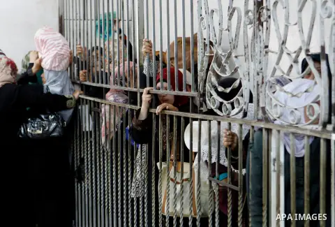 Palestinian families carry containers as they wait to receive free food for 'Iftar', the meal that breaks the daily fast during Ramadan in the West Bank city of Hebron, 13 June 2016. the "Ibrahimi Takiya" was founded in...