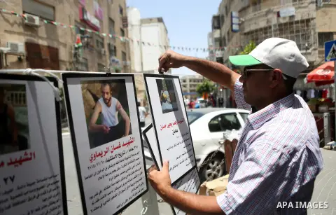 Palestinians walk past posters hanging for martyrs to show solidarity with them, in the West Bank city of Ramallah on June 13, 2016. Photo by Shadi Hatem