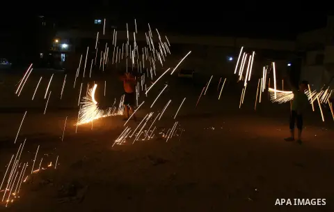 A Palestinian boy plays with fire crackers at street celebrating on the holy month of Ramadan in Rafah in the southern Gaza strip, on June 15, 2016. Ramadan is sacred to Muslims because it is during that month that tradi...