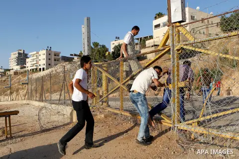 Palestinians, not permitted by Israeli security forces to cross into Jerusalem from the West Bank due to an age limit, climb an Israeli fence between the West Bank town of Bethlehem and Jerusalem as they try to make thei...