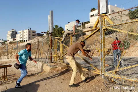 Palestinians, not permitted by Israeli security forces to cross into Jerusalem from the West Bank due to an age limit, climb an Israeli fence between the West Bank town of Bethlehem and Jerusalem as they try to make thei...