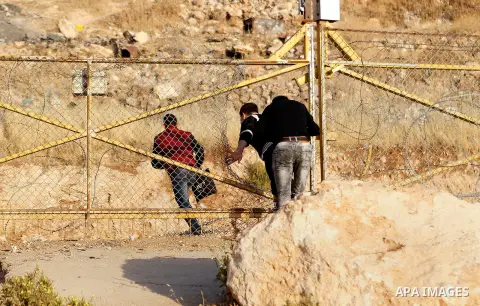 Palestinians, not permitted by Israeli security forces to cross into Jerusalem from the West Bank due to an age limit, climb an Israeli fence between the West Bank town of Bethlehem and Jerusalem as they try to make thei...