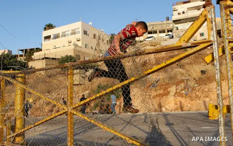 Palestinians, not permitted by Israeli security forces to cross into Jerusalem from the West Bank due to an age limit, climb an Israeli fence between the West Bank town of Bethlehem and Jerusalem as they try to make thei...