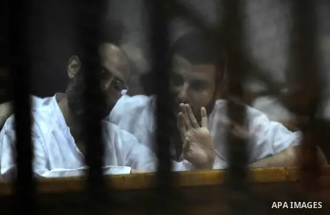 Defendants of Egyptian Muslim Brotherhood sit behind bars during their trial at a court in Cairo on June 18, 2016. An Egyptian court sentenced Morsi to life in prison in an espionage trial in which six co-defendants were...