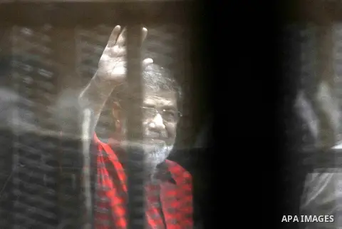 Egypt's ousted Islamist president Mohamed Morsi, wearing a red uniform, looks on from behind the defendant's bars during his trial on espionage charges at a court in Cairo on June 18, 2016. An Egyptian court sentenced Mo...