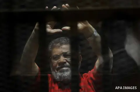 Egypt's ousted Islamist president Mohamed Morsi, wearing a red uniform, looks on from behind the defendant's bars during his trial on espionage charges at a court in Cairo on June 18, 2016. An Egyptian court sentenced Mo...