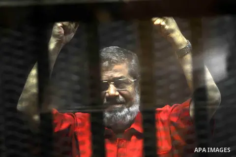 Egypt's ousted Islamist president Mohamed Morsi, wearing a red uniform, looks on from behind the defendant's bars during his trial on espionage charges at a court in Cairo on June 18, 2016. An Egyptian court sentenced Mo...