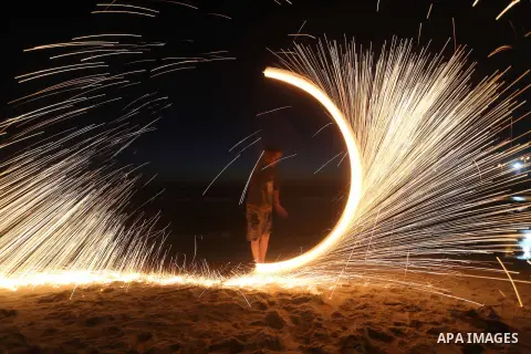 A Palestinian boy plays with fire crackers during the holy fasting month of Ramadan at the beach of the Mediterranean sea on the coast of Gaza city on June 18, 2016. Photo by Yasser Qudih
