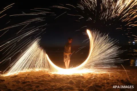 A Palestinian boy plays with fire crackers during the holy fasting month of Ramadan at the beach of the Mediterranean sea on the coast of Gaza city on June 18, 2016. Photo by Yasser Qudih