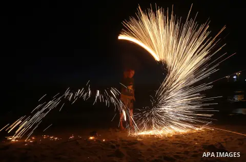 A Palestinian boy plays with fire crackers during the holy fasting month of Ramadan at the beach of the Mediterranean sea on the coast of Gaza city on June 18, 2016. Photo by Yasser Qudih