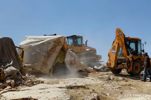 An Israeli bulldozer demolishes sheds belonging to Palestinians near the West Bank village of Yatta, south of Hebron June 19, 2016. Photo by Wisam Hashlamoun