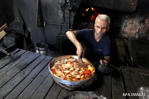 A Palestinian man cooks foods in a traditional mud oven during the holy fasting month of Ramadan, in Rafah in the southern Gaza Strip on June 19, 2016. Ramadan is sacred to Muslims because it is during that month that tr...