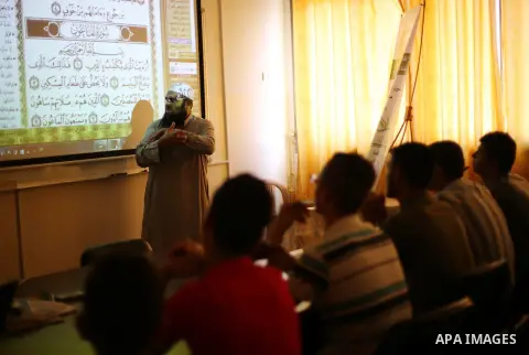 A Palestinian imam uses sign-language to teach the Koran, Islam's holy book, to deaf students at a religion school in Gaza City on June 21 2016, during the Muslim fasting month of Ramadan. Photo by Mohammed Asad