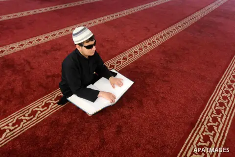 A Palestinian blind youth reads a copy of the Koran, Islam's holy book, at a religion school in Gaza City on June 21, 2016, during the Muslim fasting month of Ramadan. Photo by Mohammed Asad