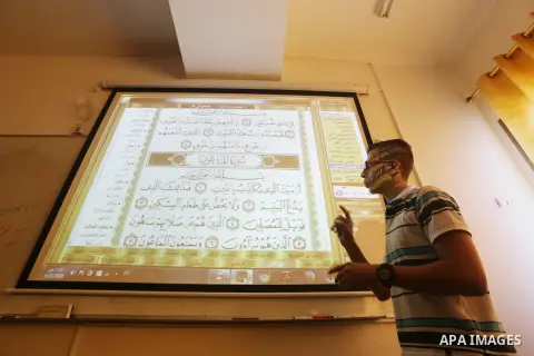 A Palestinian young man uses sign-language to read a projection of the Koran, Islam's holy book, during a class for deaf students at a religion school in Gaza City on June 21, 2016 during the Muslim fasting month of Rama...