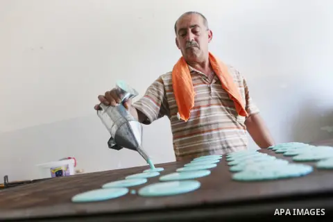 A Palestinian man prepares traditional pancakes known as ''Qatayef" at his shop during the Muslim holy fasting month of Ramadan in the West Bank village of Ein Yabrud near Ramallah on June, 21, 2016. Ramadan is sacred to...
