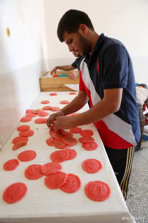 A Palestinian man prepares traditional pancakes known as ''Qatayef" at his shop during the Muslim holy fasting month of Ramadan in the West Bank village of Ein Yabrud near Ramallah on June, 21, 2016. Ramadan is sacred to...