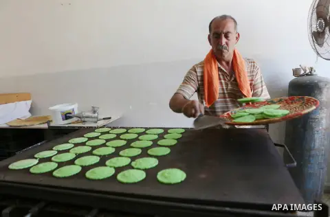 A Palestinian man prepares traditional pancakes known as ''Qatayef" at his shop during the Muslim holy fasting month of Ramadan in the West Bank village of Ein Yabrud near Ramallah on June, 21, 2016. Ramadan is sacred to...