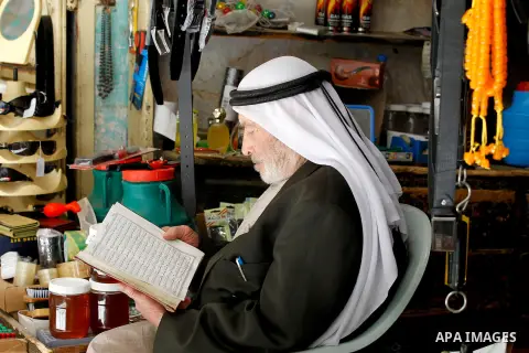A Palestinian man reads the Koran, Islam's holy book, in front of his shop at market on the holy month of Ramadan at market in the Old City of the West Bank town of Hebron on June 22, 2016. Ramadan is sacred to Muslims b...