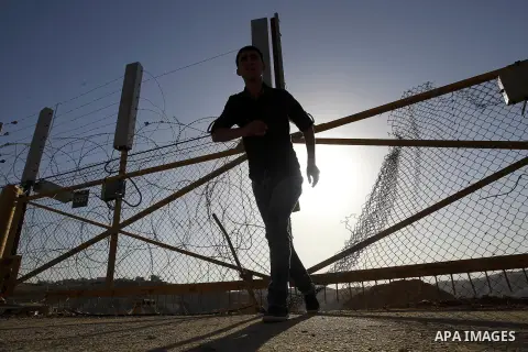 A Palestinian passes through an opening in the Israeli barrier fence as he attempts to make his way to attend the third Friday prayer of the holy fasting month of Ramadan in Jerusalem's al-Aqsa mosque, near the West bank...