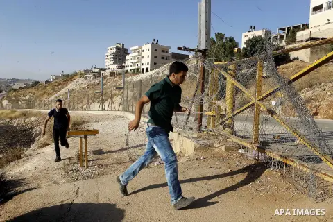 Palestinians pass through an opening in the Israeli barrier fence as they attempt to make their way to attend the third Friday prayer of the holy fasting month of Ramadan in Jerusalem's al-Aqsa mosque, near the West bank...