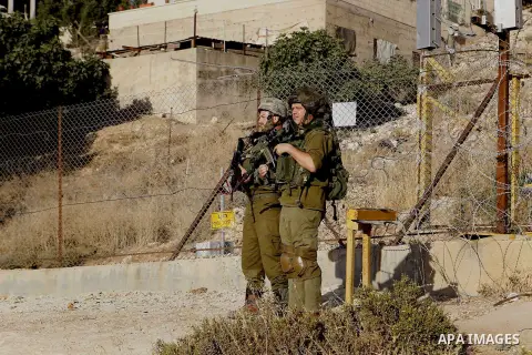 Israeli soldiers stand guard as Palestinian Muslims pass through an opening in the Israeli barrier fence as they attempt to make their way to attend the third Friday prayer of the holy fasting month of Ramadan in Jerusal...