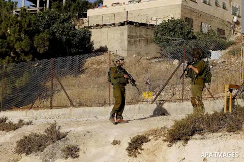 Israeli soldiers stand guard as Palestinian Muslims pass through an opening in the Israeli barrier fence as they attempt to make their way to attend the third Friday prayer of the holy fasting month of Ramadan in Jerusal...