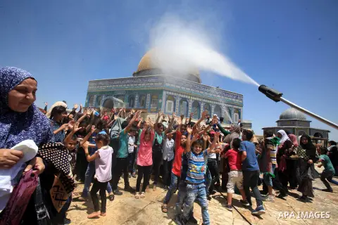 Palestinian men spray water on children to cool them down before prayers on the third Friday of the holy month of Ramadan near the Dome of the Rock, on the compound known to Muslims as Noble Sanctuary and to Jews as Temp...