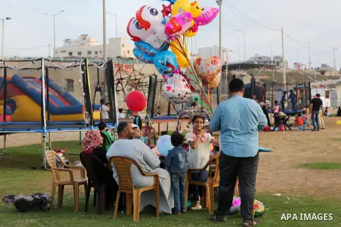 A Palestinian vendor sells ballons as Palestinian muslims prepare to break their fast on the holy fasting month of Ramadan at the beach of the Mediterranean sea on the coast of Gaza city during a hot day, on June 24, 201...