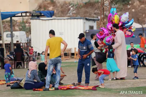 A Palestinian vendor sells ballons as Palestinian muslims prepare to break their fast on the holy fasting month of Ramadan at the beach of the Mediterranean sea on the coast of Gaza city during a hot day, on June 24, 201...