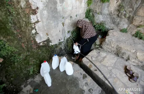 A Palestinian woman fills a jerrican with spring water on June 27, 2016 in Salfit, north of Ramallah, where some of the West Bank village's inhabitants have been without water for days. Tens of thousands of Palestinians...